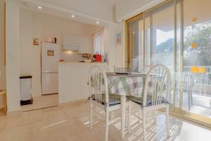 een keuken met een tafel en stoelen en een koelkast bij « Hawai » Proche Mer, Calme, Piscine in Menton