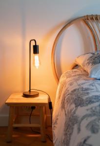 a lamp on a table next to a bed at Le Wilson - Appartement design - Hyper centre in Vichy