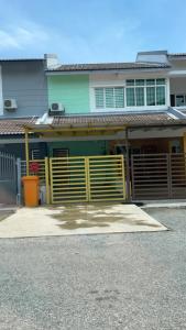 a house with a yellow gate in front of it at Purple TownHouse 3R2B Wifi in Sekinchan
