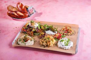 a plate of food on a pink table with bread at Allegro Neve Tzedek Boutique Suites - By HOMY in Tel Aviv