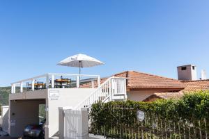 a house with a balcony with an umbrella at Glenview Heads Apartments in Knysna