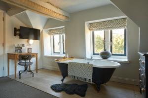 a bathroom with a tub and a desk and windows at Timbrell's Yard in Bradford on Avon