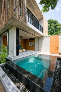 a swimming pool in front of a house at Cape Pakarang Wow Wild Wellness Escapes in Khao Lak