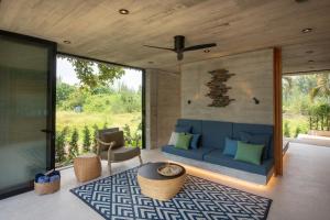 a living room with a blue couch and a large window at Cape Pakarang Wow Wild Wellness Escapes in Khao Lak