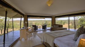 Schlafzimmer mit einem Bett, einem Tisch und Stühlen in der Unterkunft Kicheche Valley Camp in Naboisho
