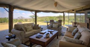 a living room with couches and a table in a tent at Kicheche Valley Camp in Naboisho