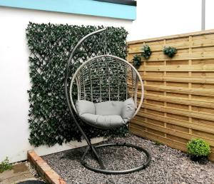 a rattan chair in front of a fence at Glos Homes Presents - Old Coach House a Quiet Place near Town Centre in Cheltenham