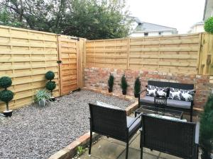 a patio with two chairs and a fence at Glos Homes Presents - Old Coach House a Quiet Place near Town Centre in Cheltenham