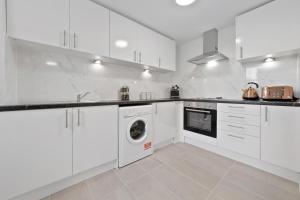 - une cuisine avec des placards blancs et un lave-linge/sèche-linge dans l'établissement Stunning Ensuite Room Crystal Palace London SE20, à Londres