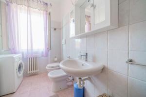 La salle de bains blanche est pourvue d'un lavabo et de toilettes. dans l'établissement A Casa di Coco - Goelba, à Portoferraio