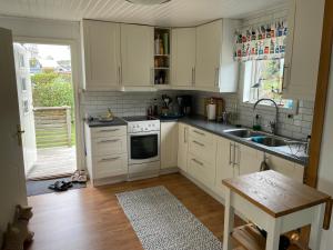 a kitchen with white cabinets and a sink and a table at Havsnära stuga, Falkenberg in Falkenberg +13 photos