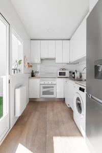 cocina con armarios blancos, lavadora y secadora en Cozy 2 bedroom apartment with patio en Madrid