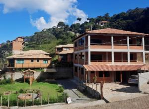 um grupo de casas com uma colina ao fundo em Casa Amantes da Serra Ibitipoca - Sua melhor opção! em Conceição do Ibitipoca