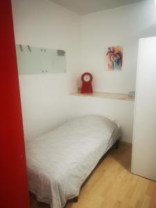 Bett in einem Zimmer mit einer weißen Wand in der Unterkunft Studio - un lit en ville in Ath