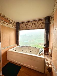 eine Badewanne im Bad mit einem großen Fenster in der Unterkunft ดอยหมอกดอกไม้รีสอร์ท DoiMok DokMai Resort in Mae Salong
