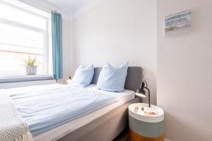 a bedroom with a bed with white sheets and a window at Steger-Hüs Wohnung 05 in Rantum
