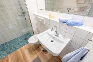 a white bathroom with a sink and a shower at Steger-Hüs Wohnung 05 in Rantum +13 photos