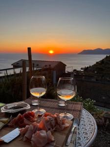 einen Tisch mit zwei Weingläsern und einem Teller Essen in der Unterkunft Sunset Manarola in Manarola