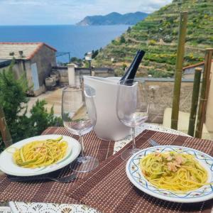 zwei Teller Pasta auf einem Tisch mit Weingläsern in der Unterkunft Sunset Manarola in Manarola