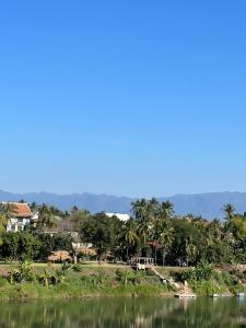 une maison sur une colline à côté d'une masse d'eau dans l'établissement Namkhan Riverview Aphay, à Luang Prabang