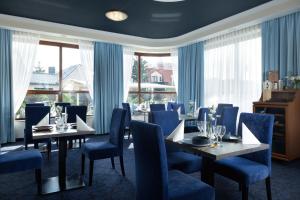 a dining room with tables and chairs and windows at Villa Hoff Wellness & Spa in Trzęsacz