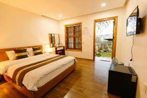 a bedroom with a bed and a flat screen tv at VANDA VIilla Garden trung tâm in Da Lat