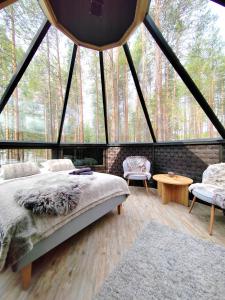a bedroom in a tent with a bed and two chairs at LakeLodge Kiehinen & Igloos in Rovaniemi