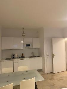 a kitchen with white cabinets and a table and a refrigerator at Large Studio 907T near Monte Carlo Casino Monaco in Monte Carlo