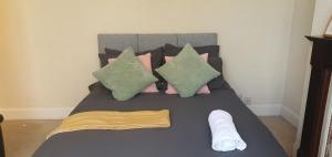 ein Bett mit rosa und grünen Kissen und einem Handtuch darauf in der Unterkunft Coventry Spacious Rooms In City in Coventry