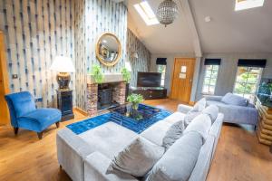 a living room with a large couch and a tv at The Hollies Forest Lodges in Cuddington