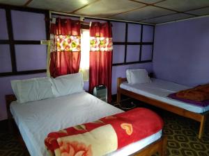 a bedroom with two beds and a window with red curtains at Hillsation Thulung Homestay in Kalimpong