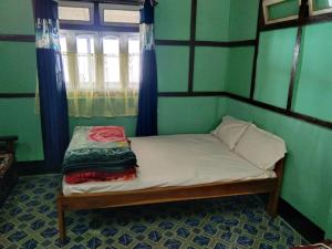 a small bed in a room with a window at Hillsation Thulung Homestay in Kalimpong