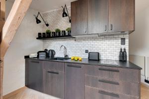 uma cozinha com armários de madeira e um lavatório em Lion Apartments - Modern Attic em Sopot