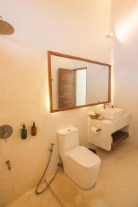 uma casa de banho com um WC, um lavatório e um espelho. em SEACLUB Siargao em General Luna