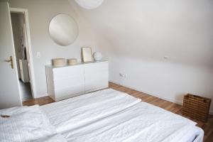 a white bedroom with a bed and a mirror at DG-Wohnung mit sonnigem Balkon in Marburg an der Lahn