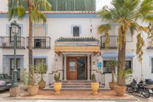 a white building with palm trees in front of it at Apartamentos Playamaro in Maro