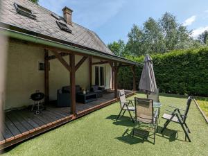 a deck with chairs and an umbrella and a grill at Rekreační dům KRKONOŠE - Ubytování - Holidayhome Lampertice in Lampertice