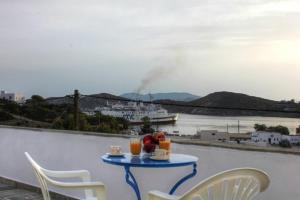 a table with drinks on a balcony with a cruise ship at Violetta in Ios Chora +5 photos