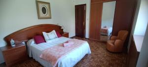 - une chambre avec un lit, une chaise et un miroir dans l'établissement Casa Ruán, à Carnota