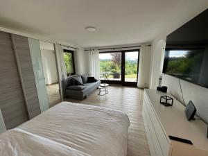 a bedroom with a large white bed and a couch at Modernes Apartment mit 180° Bergblick in Buchenberg