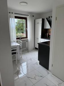 uma cozinha branca com uma mesa e uma janela em Modernes Apartment mit 180° Bergblick em Buchenberg