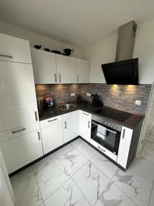 uma cozinha com armários brancos e um lavatório em Modernes Apartment mit 180° Bergblick em Buchenberg