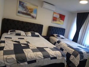 a bedroom with two beds and two windows at Old House Apartment in Prishtinë