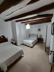 1 dormitorio con 2 camas y lámpara de araña en Casa Rural Nueva Araceli en Oliete