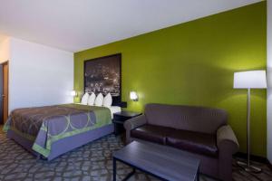 a hotel room with a bed and a couch at Super 8 by Wyndham De Soto in De Soto +26 photos