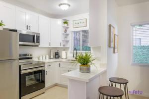 una cucina con armadi bianchi e un bancone con sgabelli di Hidden Gem Apt/near downtown Miami & Brickell a Miami