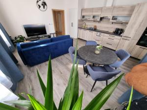 ein Wohnzimmer mit einem Tisch und einem blauen Sofa in der Unterkunft Luxusní apartmán 3KK u náměstí - Klicperova in Hradec Králové