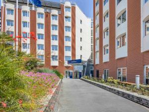 una pasarela frente a un edificio con flores rosas en Novotel Salerno Est Arechi, en Salerno