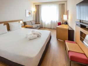 ein Hotelzimmer mit einem großen weißen Bett und einem Sofa in der Unterkunft Novotel Salerno Est Arechi in Salerno