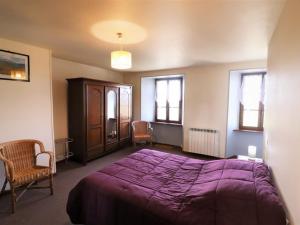 um quarto com uma cama roxa e 2 cadeiras em Gîte Montboudif, 3 pièces, 4 personnes - FR-1-742-59 